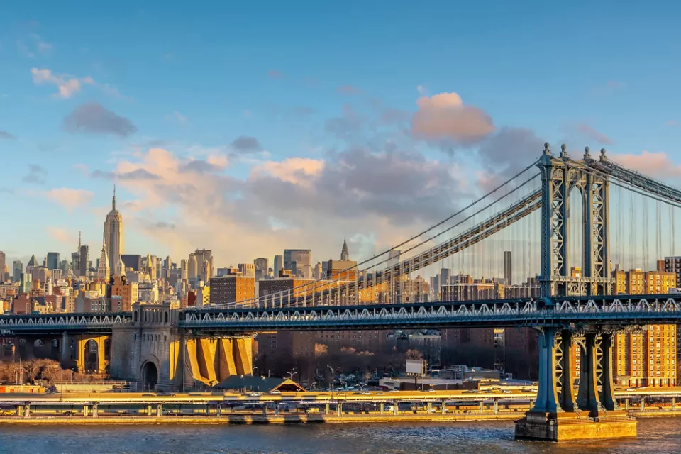 A view of the Manhattan Bridge with the Empire State Building in the distance.